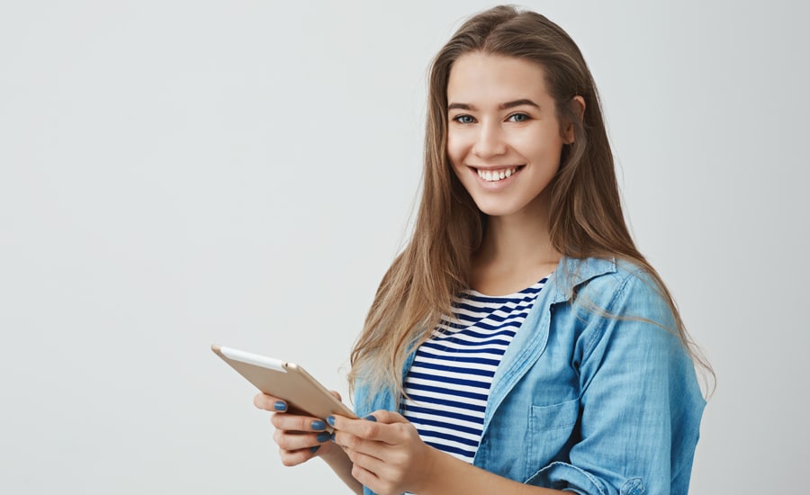 Mujer sonríe mientras observa información de factura electrónica en su tablet